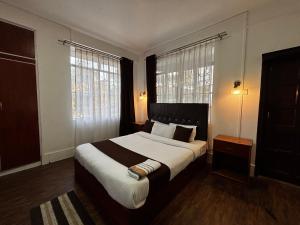 a bedroom with a large bed and two windows at JKR residency in Shillong