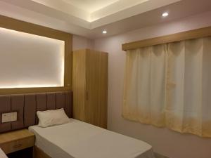 a small bedroom with a bed and a window at Hotel Niko International in Bodh Gaya