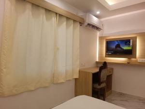 a room with a white curtain and a television at Hotel Niko International in Bodh Gaya