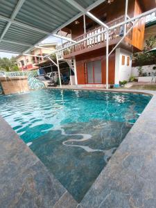 a swimming pool in front of a house at Puerto Galera Transient Kubo Guest Place in Puerto Galera