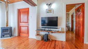 a living room with a television and a wooden floor at Oystercatcher Guest House in Wilderness