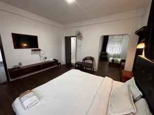 a bedroom with a white bed and a tv on the wall at JKR residency in Shillong