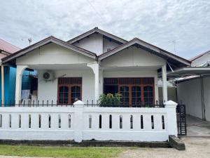 a white house with a white fence in front of it at Zethira Homestay Syariah in Tabing