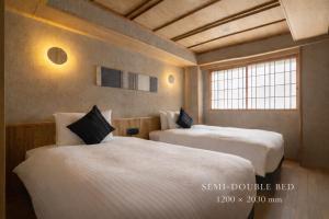 two beds in a room with two windows at soyo-ne kyoto sanjo in Kyoto