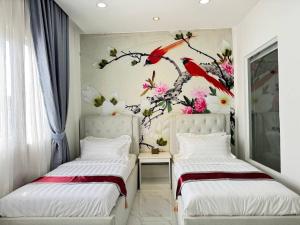 two beds in a room with a bird mural on the wall at Center Point Resident in Phnom Penh