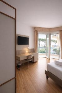 a bedroom with a bed and a desk and a television at LVG Hotel Collection - Majestic in Alassio