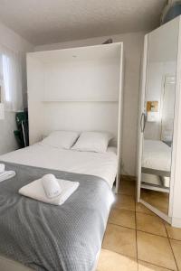 a bedroom with a large white bed and a mirror at Studio cabine climatise Malibu Village in Canet-en-Roussillon