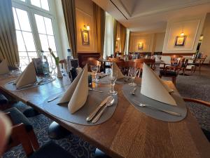 a long wooden table with silverware and napkins on it at Hotel Der Lindenhof in Gotha