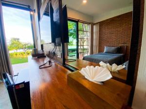 a living room with a table and a bed and a television at บ้านเคียงสะหวัน in Muang Phaluka