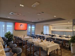 a dining room with tables and chairs and a screen at Hotel Aurel in Podgorica