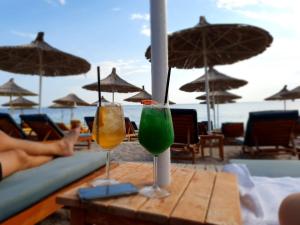 a table with two drinks on a beach with umbrellas at Apartments Vista Mar in Orikum