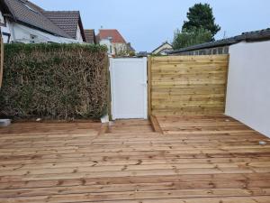 a wooden patio with two doors and a fence at Charmante maison de bord de mer avec terrasse in Luc-sur-Mer +12 photos