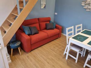 a living room with a red couch and a staircase at Charmante maison de bord de mer avec terrasse in Luc-sur-Mer