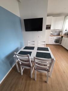 a kitchen with a table and two chairs and a television at Charmante maison de bord de mer avec terrasse in Luc-sur-Mer