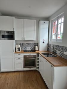 a white kitchen with white cabinets and a sink at Charmante maison de bord de mer avec terrasse in Luc-sur-Mer
