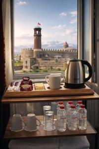 a shelf with water bottles and a tea pot and a window at Arı Otel in Erzurum