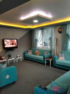 a living room with blue couches and a flat screen tv at Arı Otel in Erzurum