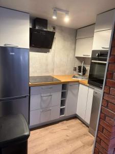 a kitchen with white cabinets and a black refrigerator at Tęczowy Domek - Balia z hydromasażem in Darłowo