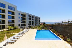 a swimming pool with lounge chairs and a building at Star Light Apartment in Câmara de Lobos