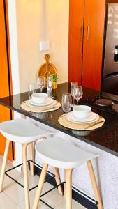 a kitchen counter with two stools with plates and wine glasses at 12th on The Bay Apartment in Richards Bay