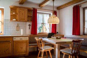a kitchen with a wooden table and red curtains at Ferienhaus-Pitztal in Wenns