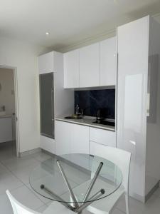a glass table and two white chairs in a kitchen at Studio on Main in Langebaan