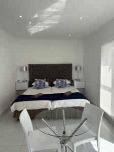 a bedroom with a bed with two chairs and a glass table at Studio on Main in Langebaan