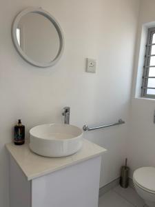 a white bathroom with a sink and a mirror at Studio on Main in Langebaan