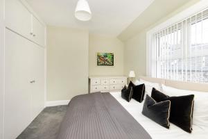 a bedroom with a large white bed with black pillows at Cosy town centre cottage in Peebles