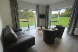 a living room with a couch and chairs and windows at Le Grand Pont in Vielsalm