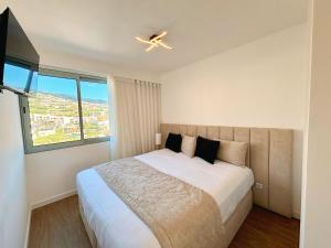 a bedroom with a large bed with a ceiling fan at Star Light Apartment in Câmara de Lobos +26 photos