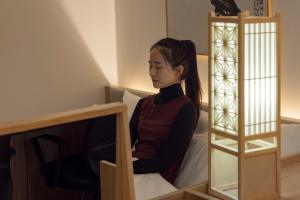 a woman sitting on a bed in a room at Bucheon Daon Hotel in Bucheon
