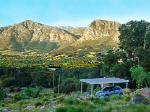 a car parked under a canopy in front of mountains at Stonehedge Cottages in Franschhoek