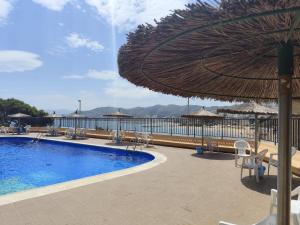 a resort with a pool and an umbrella and chairs at Isla de los Pensamientos in Faro de Cullera