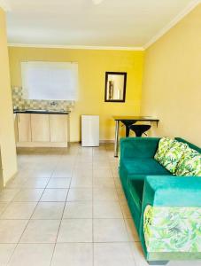 a living room with a green couch and a table at Druza’s guest house in Rustenburg