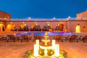 a courtyard with a fountain in front of a pool at Hotel Sunset Palace Merzouga in Merzouga
