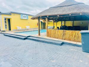a yellow house with a swimming pool with a thatch roof at Druza’s guest house in Rustenburg