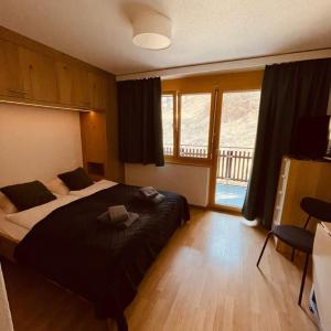 a bedroom with a large bed and a balcony at Studio Vitalis in Zermatt