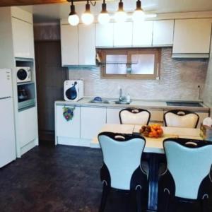a kitchen with white cabinets and a table and chairs at Rabit Island healing house in Jeju