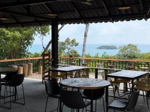 a patio with tables and chairs and a view of the ocean at Hillside Hostel & Bungalows in Kaôh Rŭng (3)