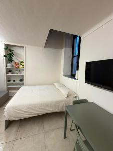 a bedroom with a bed and a desk and a flat screen tv at Casa Bago in Ivrea