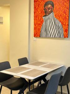 a table in a room with chairs and a painting at Jenn Suites - Nakuru Town in Nakuru