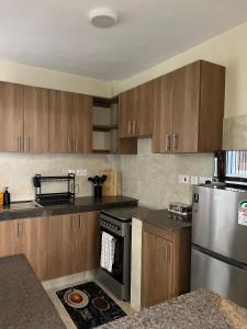 a kitchen with wooden cabinets and a stainless steel refrigerator at Jenn Suites - Nakuru Town in Nakuru
