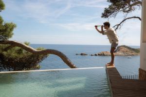a man standing on the edge of a swimming pool at BYPILLOW Cap Sa Sal in Begur
