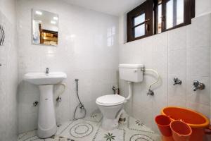 a white bathroom with a toilet and a sink at Rainbow Palace Pahalgam in Pahalgām
