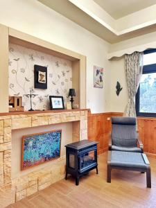 a living room with a fireplace and a chair and a television at 日月潭 讀好聚民宿 2-22人 一次只接待一組 in Yuchi