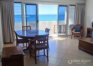 a dining room with a table and chairs and the ocean at Above The Dunes in Woorim