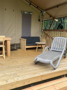 a chair on a wooden deck with a tent at Glampingtent Serengeti in Zwartemeer