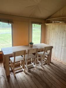 a dining room with a wooden table and chairs at Glampingtent Serengeti in Zwartemeer