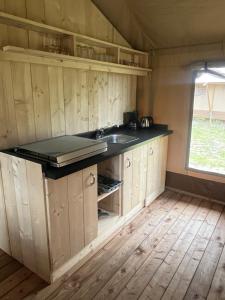 a kitchen with wooden cabinets and a sink at Glampingtent Serengeti in Zwartemeer